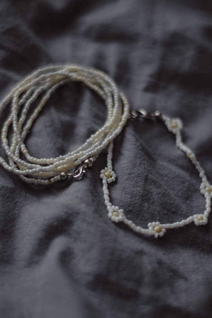 White beaded necklaces rest on gray fabric.
